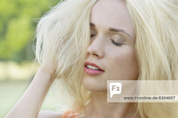 Young woman with hand in hair  eyes closed  portrait