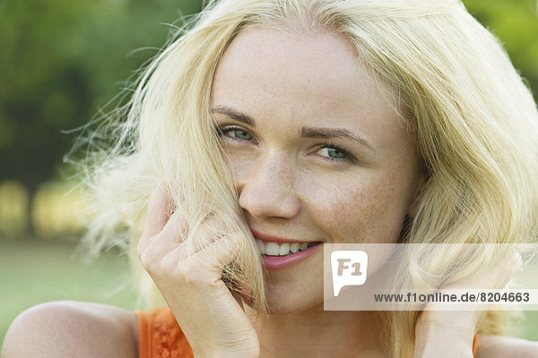 Young woman with hands in hair  smiling  portrait