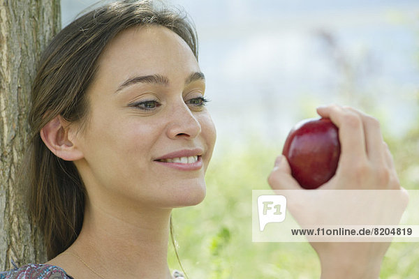 Frau im Freien sitzend mit Apfel