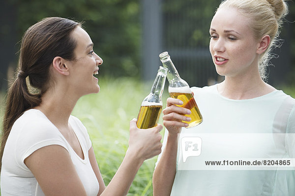 Frauen  die zusammen trinken  klirrende Flaschen.