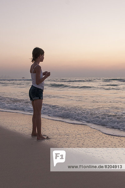 Mädchen am Strand stehend mit Blick aufs Meer