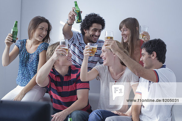 Friends watching sports match on television together celebrate team's victory
