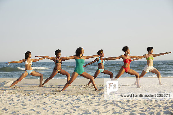 Frauen Übendes Yoga am Strand