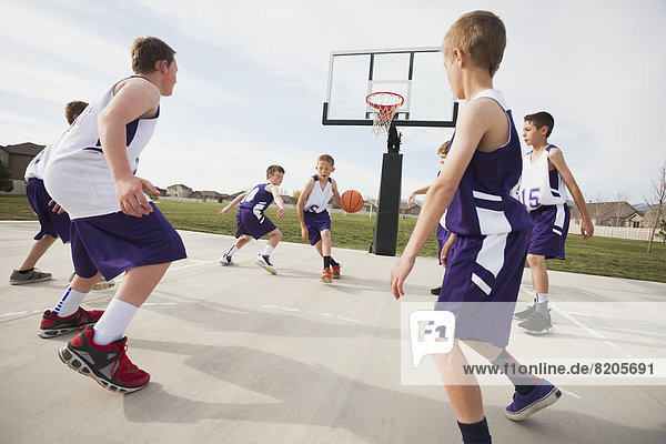 Caucasian boys playing basketball on court