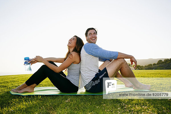 Couple sitting on yoga mat in park