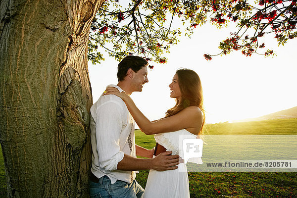 Couple hugging by tree in park
