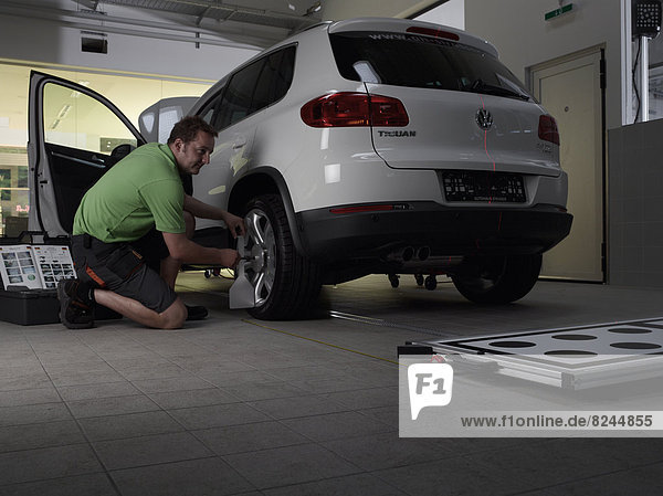 Car mechanic taking axis measurements with a laser  VW Strasser  Volkswagen car repair shop