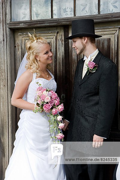 Bride and groom standing in front of wooden door