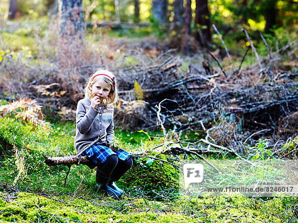 Girl sitting on log in forest