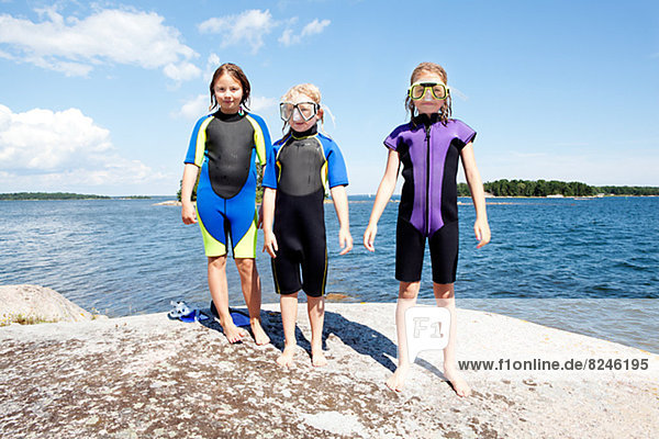 Three girls in swimwear by lake