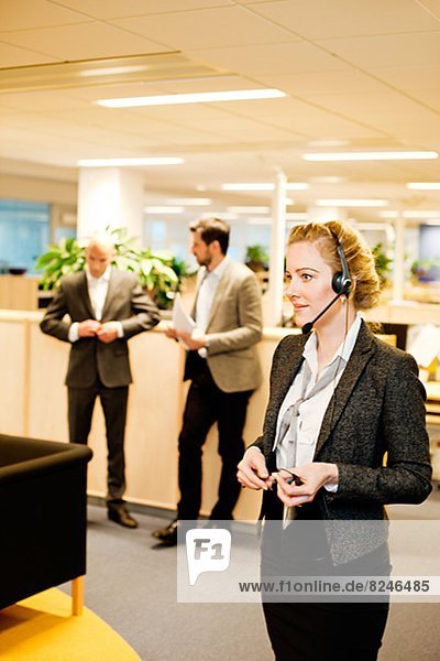 Young businessman on phone in office  colleagues in background