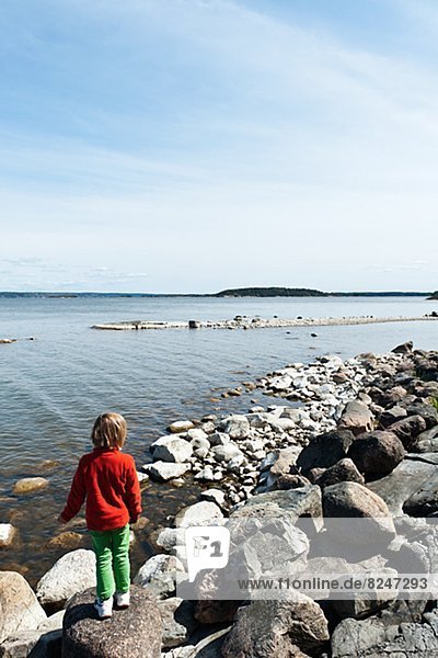 Girl standing on rocky coast