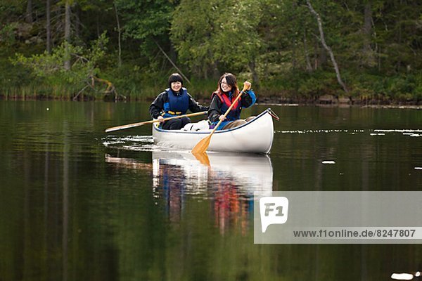 Two women rowing at lake