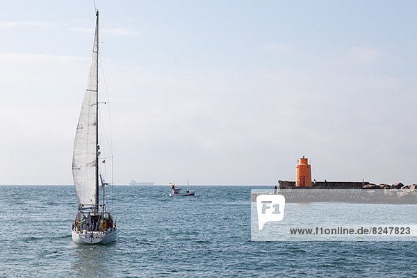 Sailing boat on sea  lighthouse in background