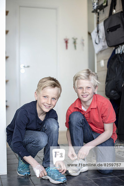 Porträt von lächelnden Jungen mit Schnürsenkeln am Boden