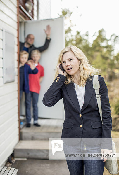 Frau mit Handy und Familie im Hintergrund