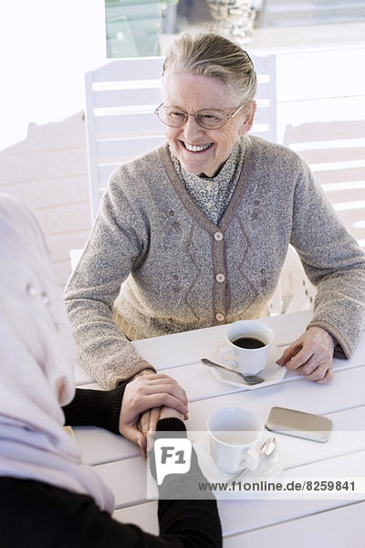 Junge Hausfrau tröstende Seniorin beim Kaffee auf der Veranda