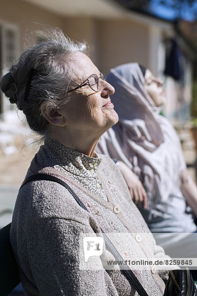 Seniorin und Heimpflegerin entspannt vor dem Haus
