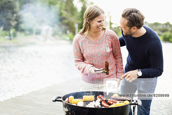 Happy couple looking at each other while barbecuing on pier