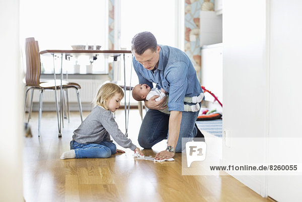 Vater putzt den Boden mit der Tochter und hält das Mädchen zu Hause.