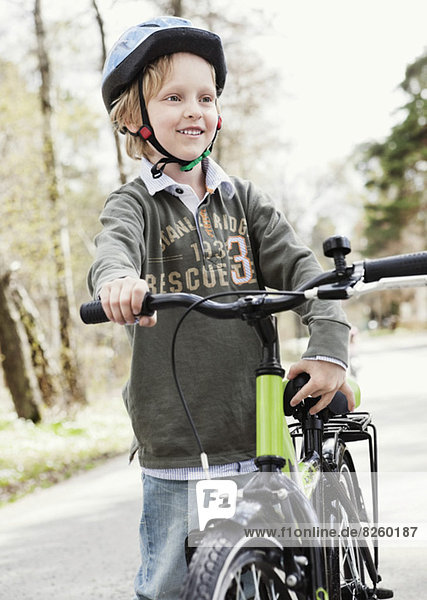 Happy boy with bicycle standing on road