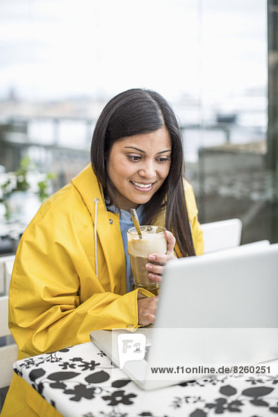 Geschäftsfrau mit Laptop beim Milchshake im Café