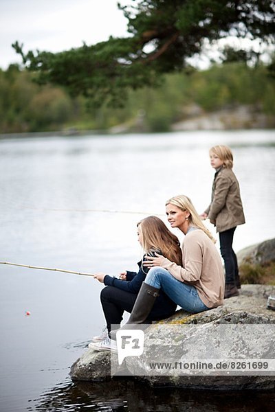 Mother with two kids fishing at lake