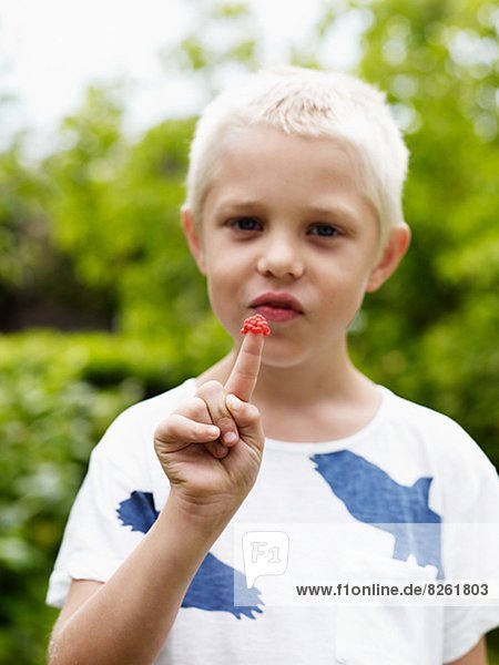 Portrait of boy with raspberry on finger
