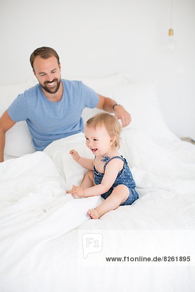Father and little daughter playing in bed