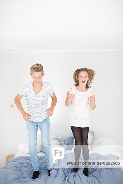 Brother and sister jumping on bed