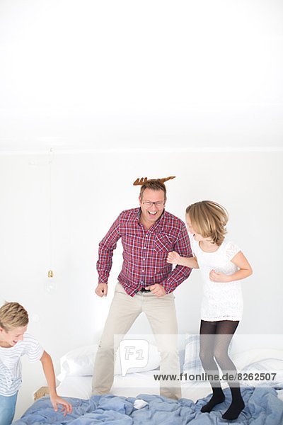 Father with children jumping on bed