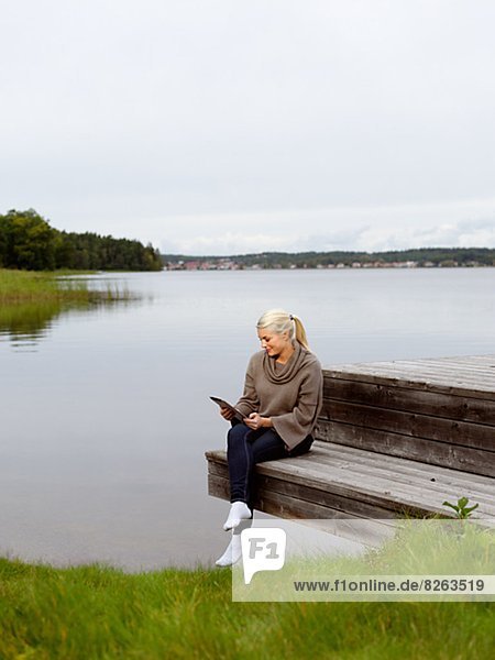 Smiling woman on jetty with digital tablet