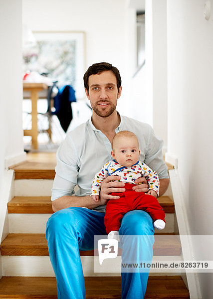 Portrait of father with baby sitting on floor