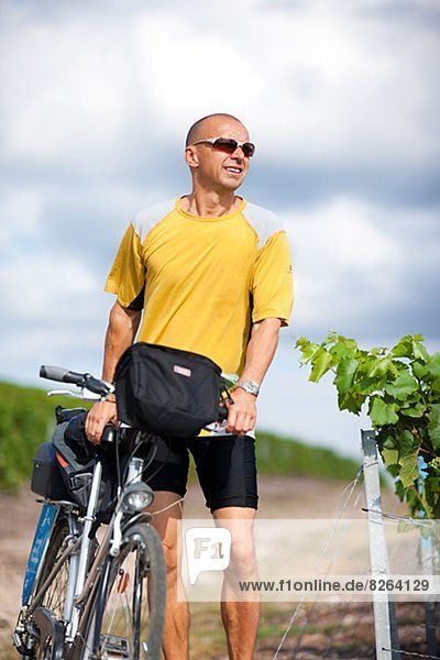 Cyclist with map in vineyard