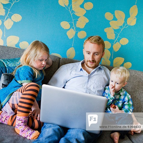 Father with daughter and son using laptop