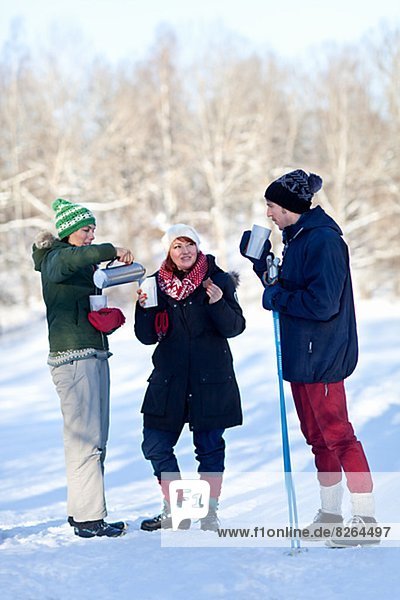 Three people cross country skiing and having coffee