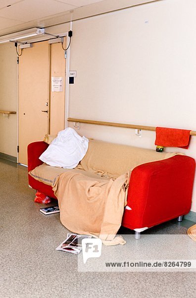 Red sofa with pillow and blanket in hospital corridor