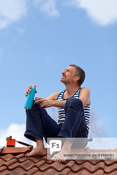 Mature man having coffee break on top of roof