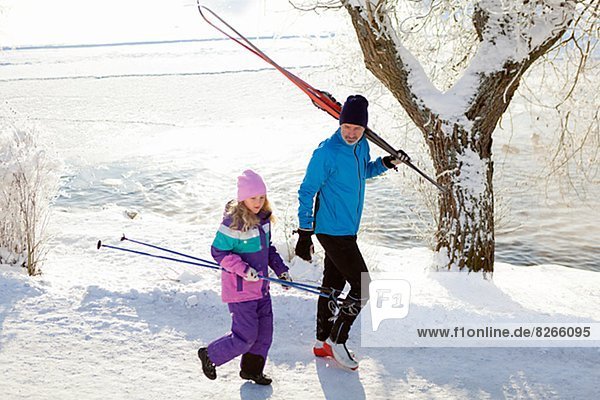 Father with daughter walking with skis