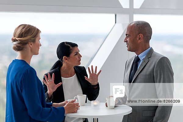 Businessman and businesswomen talking while drinking coffee