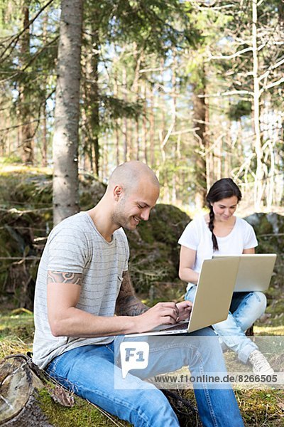 Couple in forest using laptops  Sweden