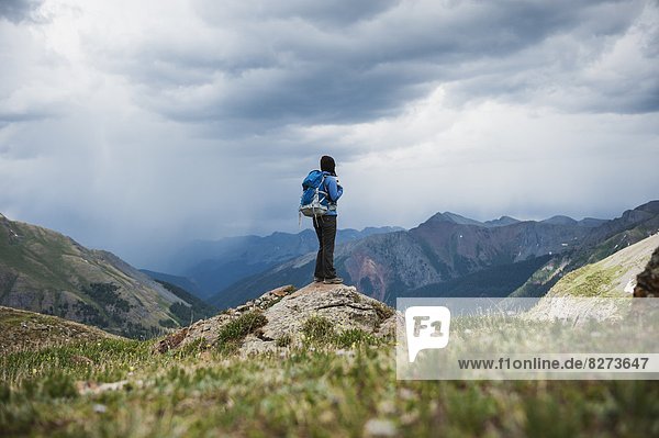 Female hiker watches approaching thunderstorms from Ice Lakes Basin  San Juan mountains  Colorado  USA