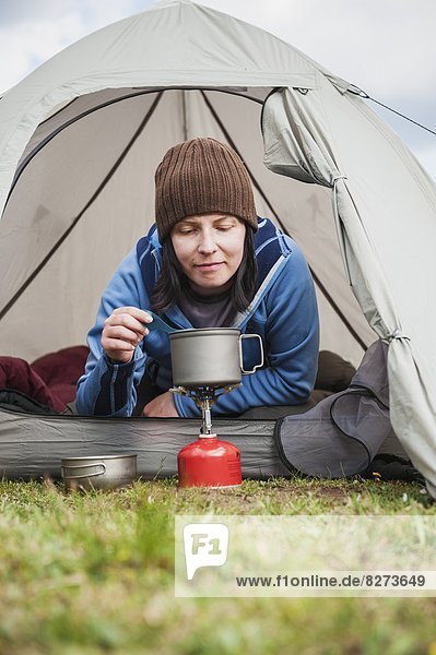 Female backpacker cooks from entrance of tent