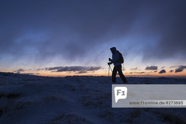 Silhouette of hiker on wintry summit of Corn Du at dawn  Brecon Beacons national park  Wales
