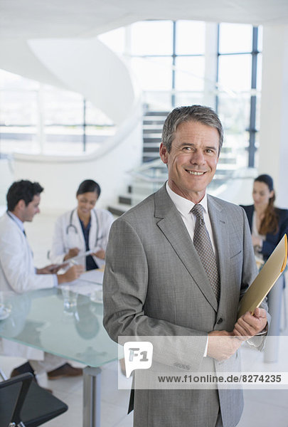 Porträt eines lächelnden Geschäftsmannes im Gespräch mit Ärzten