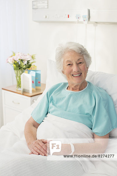 Porträt eines lächelnden alternden Patienten im Krankenhausbett