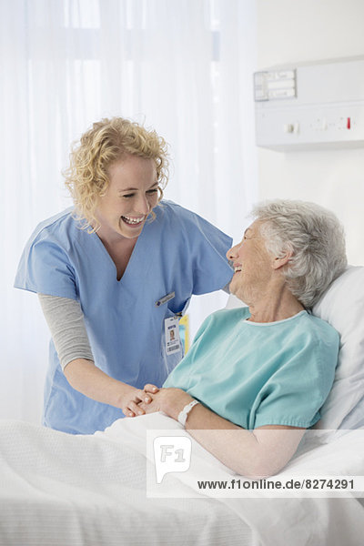 Krankenschwester und älterer Patient sprechen im Krankenhauszimmer