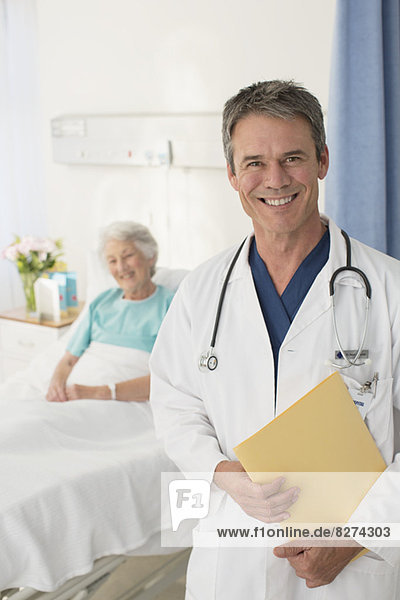 Porträt des lächelnden Arztes mit Patient im Hintergrund