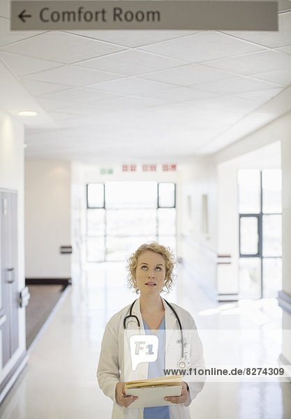Arzt schaut auf das Schild im Flur des Krankenhauses