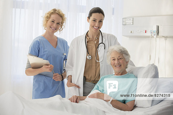 Doctor  nurse and senior patient smiling in hospital room